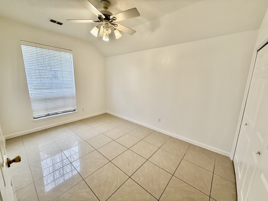 604 Cactus Bend Drive Pflugerville, TX 78660 - Photo 19 of 29 Spare room featuring light tile patterned floors, a textured ceiling, lofted ceiling, and a ceiling fan