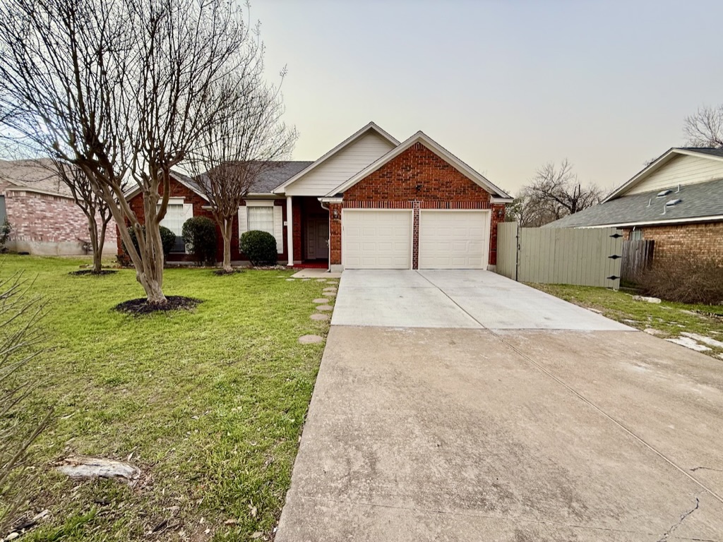 604 Cactus Bend Drive Pflugerville, TX 78660 - Photo 2 of 29 Ranch-style house with driveway, brick siding, an attached garage, fence, and a front yard