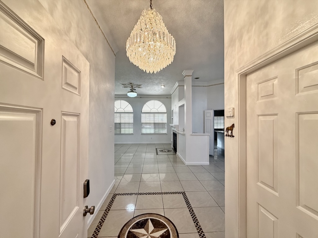604 Cactus Bend Drive Pflugerville, TX 78660 - Photo 4 of 29 Hall featuring light tile patterned floors, baseboards, a chandelier, and a textured ceiling