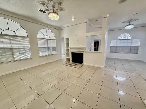 an empty room with windows and fireplace