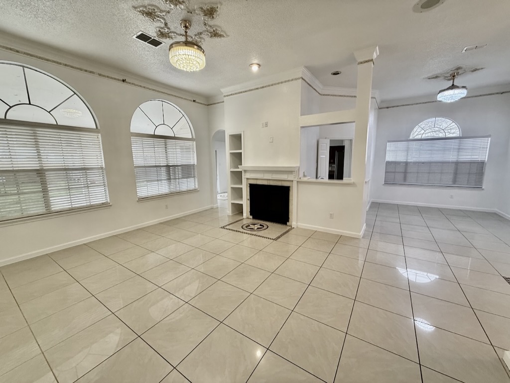 604 Cactus Bend Drive Pflugerville, TX 78660 - Photo 6 of 29 Unfurnished living room with light tile patterned floors, baseboards, visible vents, and a textured ceiling