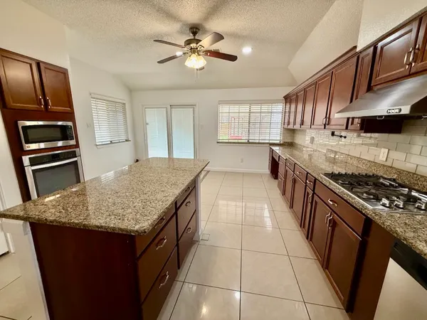 a kitchen with stainless steel appliances granite countertop a stove a sink dishwasher and a refrigerator