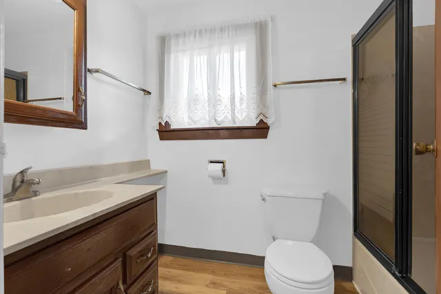 a bathroom with a sink a toilet a mirror and a window