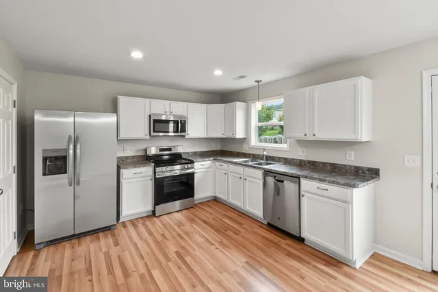 a kitchen with granite countertop a refrigerator stove top oven and sink