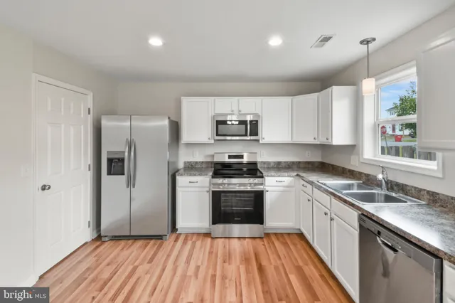 a kitchen with stainless steel appliances granite countertop a stove a sink and a refrigerator