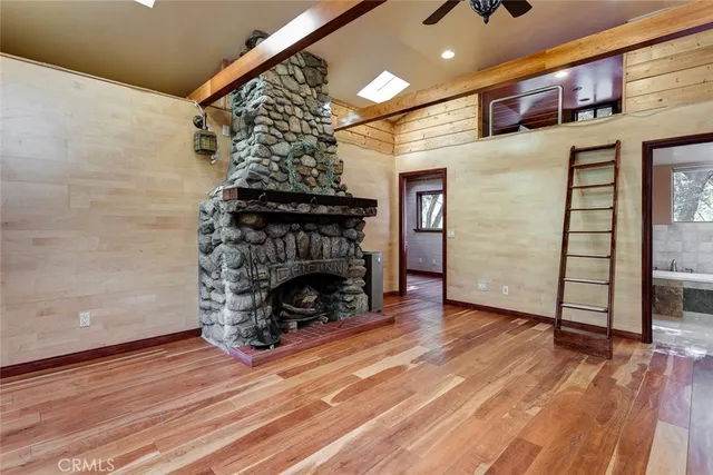a view of an empty room with wooden floor fireplace and a window