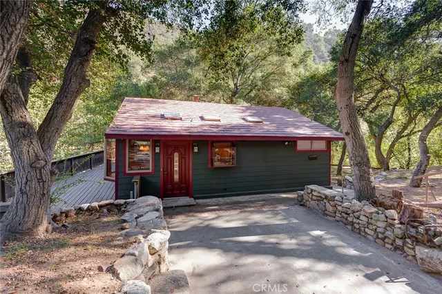 a view of a house with a small yard and large tree