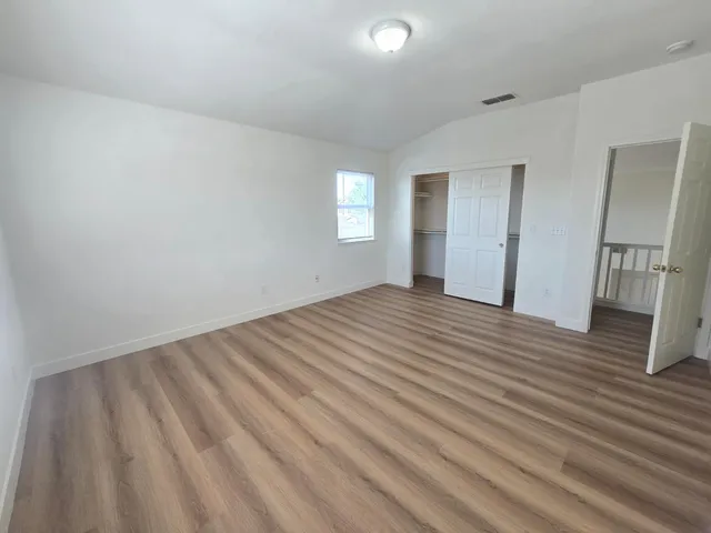 a view of empty room with wooden floor and fan