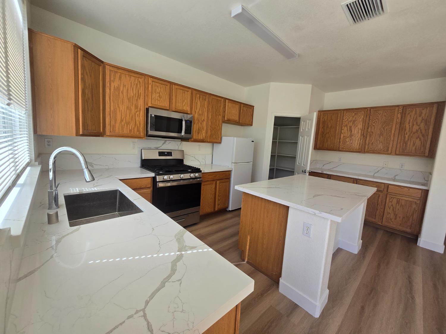 10554 Rudder Way Stockton, CA 95209 - Photo 27 of 40 a kitchen with stainless steel appliances a stove a sink a microwave a refrigerator a cabinets and wooden floor