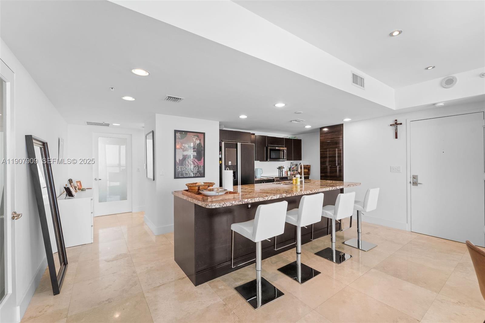 665 Northeast 25th Street, Unit PHI01 Miami, FL 33137 - Photo 12 of 38 a dining area with stainless steel appliances kitchen island granite countertop a dining table chairs and a refrigerator