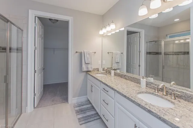 a bathroom with double vanity sinks and a shower