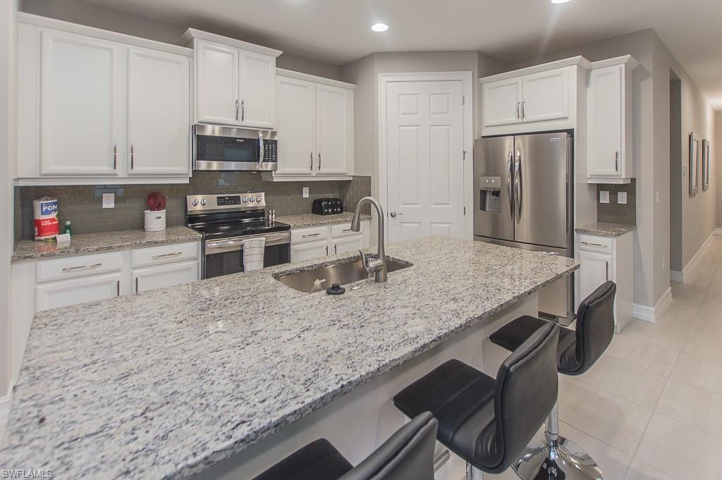14670 Catamaran Place Naples, FL 34114 - Photo 7 of 24 a kitchen with stainless steel appliances granite countertop a sink stove and refrigerator