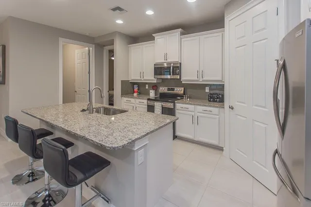 a kitchen with stainless steel appliances a sink a stove a refrigerator cabinets and a dining table