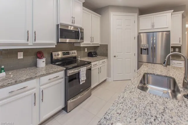 a kitchen with stainless steel appliances granite countertop a stove a refrigerator and a white cabinets