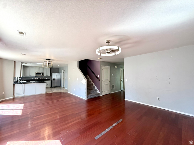 Wood-finish flooring throughout, kitchen with light gray cabinetry, stainless steel appliances, and a central island