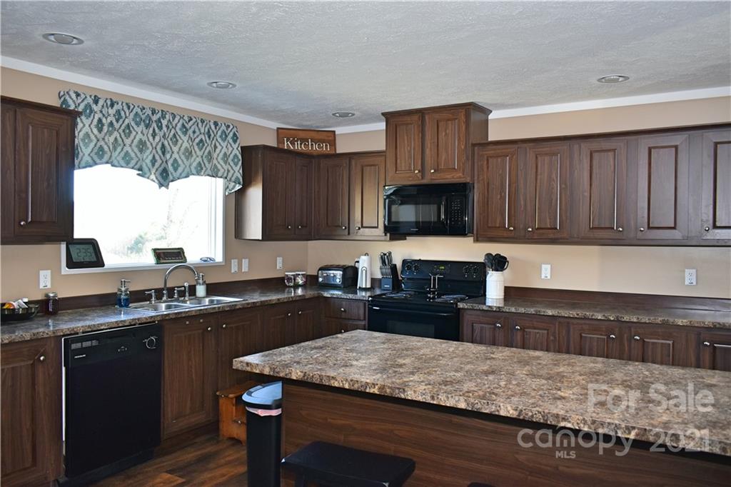 11 Fernwood Road Clyde, NC 28721 - Photo 10 of 26 a kitchen with a sink a stove a microwave and wooden cabinets