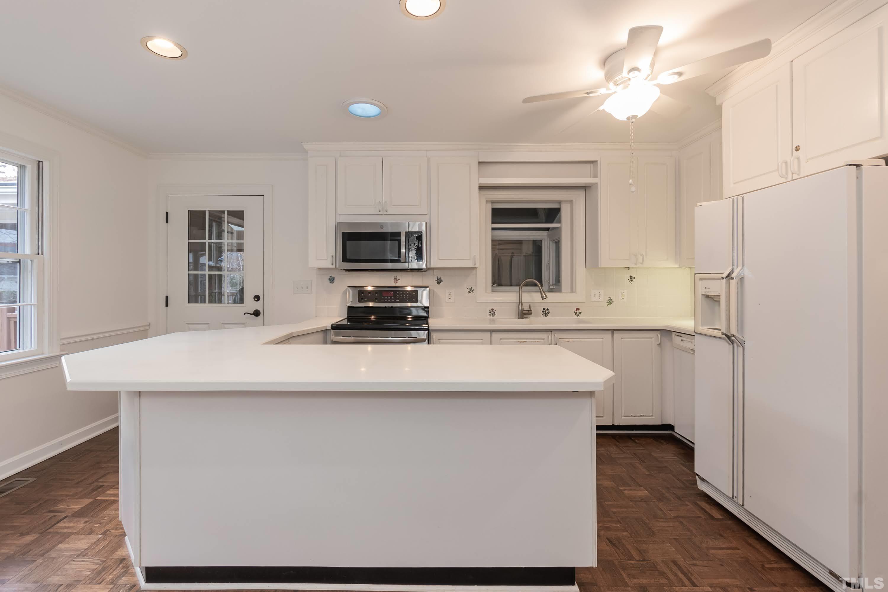 1104 Deboy Street Raleigh, NC 27606 - Photo 11 of 38 a kitchen with kitchen island a stove a sink and a refrigerator with wooden floor