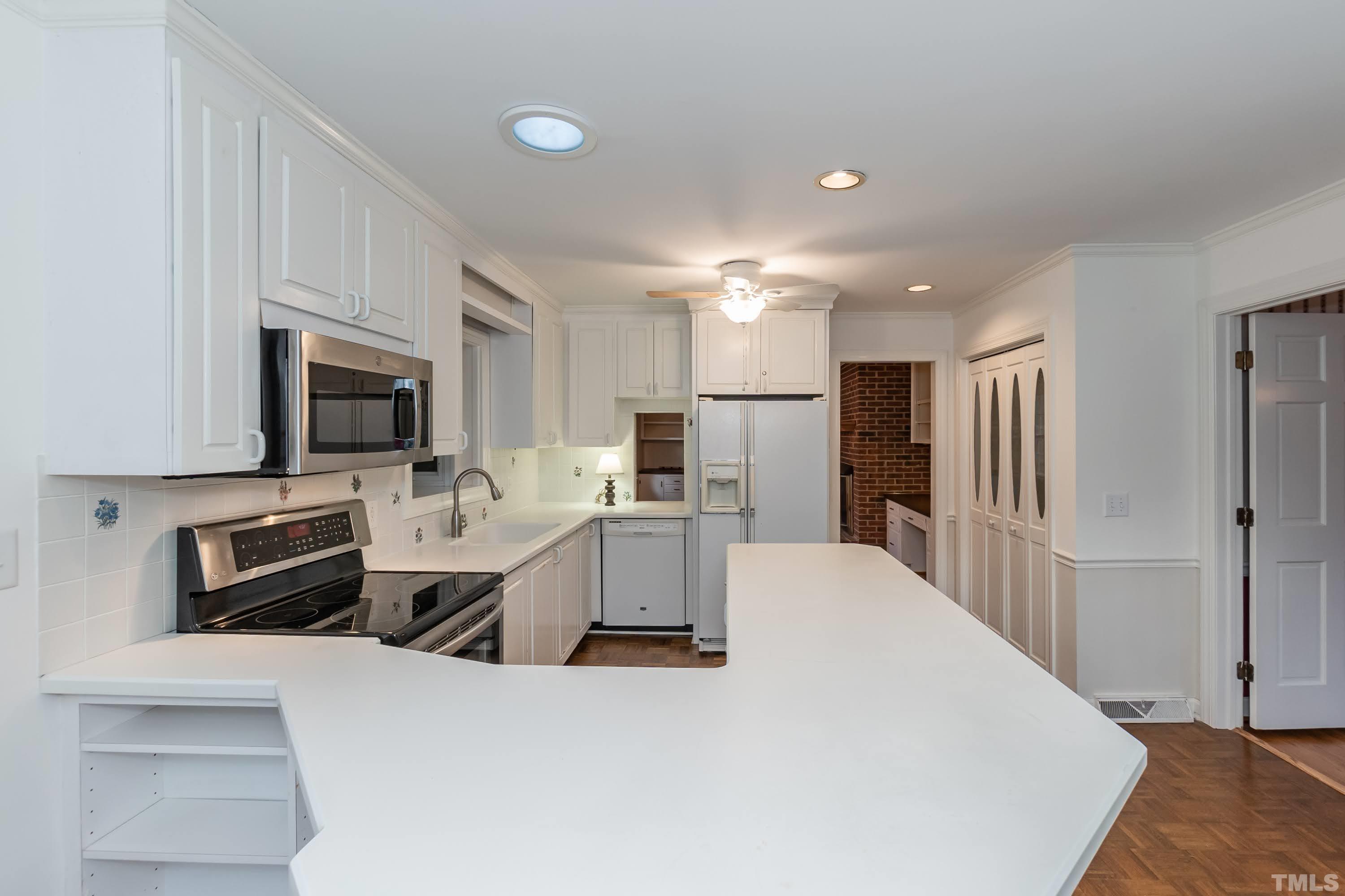 1104 Deboy Street Raleigh, NC 27606 - Photo 7 of 38 a large kitchen with stainless steel appliances a refrigerator a stove a sink a microwave and wooden cabinets