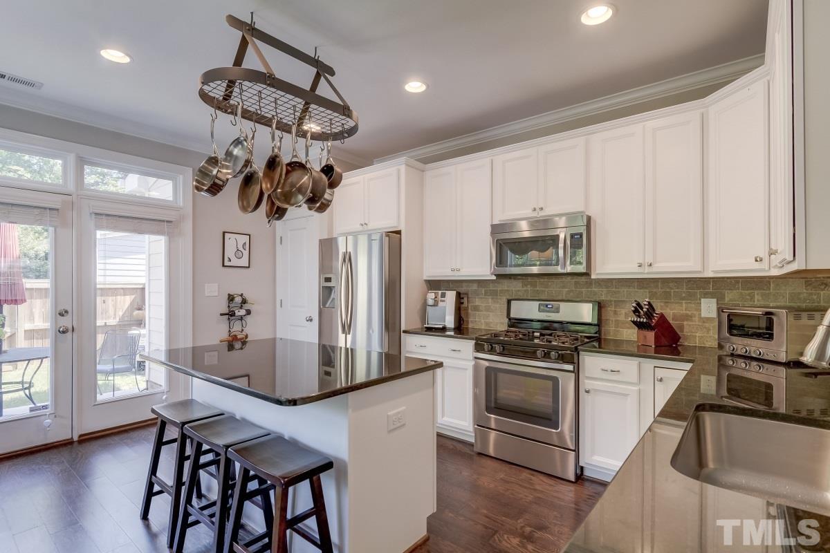 527 Ledbetter Court Raleigh, NC 27608 - Photo 7 of 13 a kitchen with stainless steel appliances granite countertop a stove a refrigerator a sink dishwasher a dining table and chairs with wooden floor