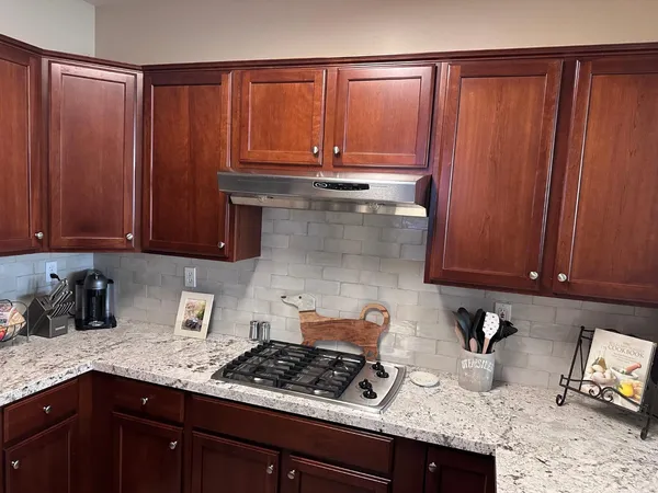 a kitchen with granite countertop stainless steel appliances wooden cabinets and a sink