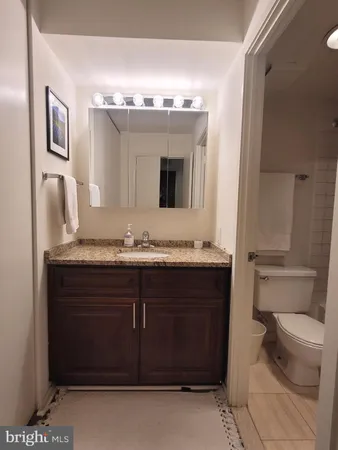 a bathroom with a granite countertop sink a toilet and mirror