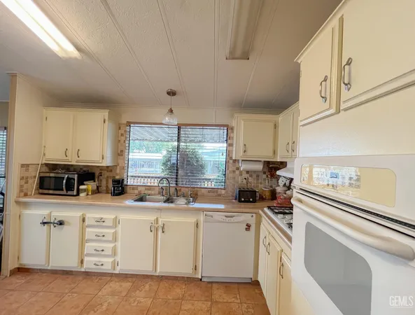 a kitchen with cabinets appliances a sink and a window