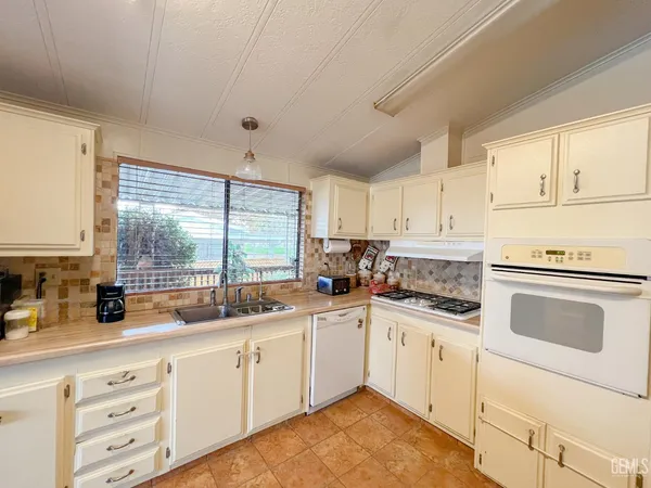 a kitchen with granite countertop a sink cabinets stainless steel appliances and a window