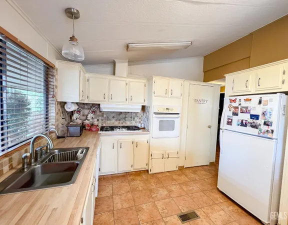 a kitchen with granite countertop a refrigerator a sink dishwasher a stove a washer and dryer with wooden floor