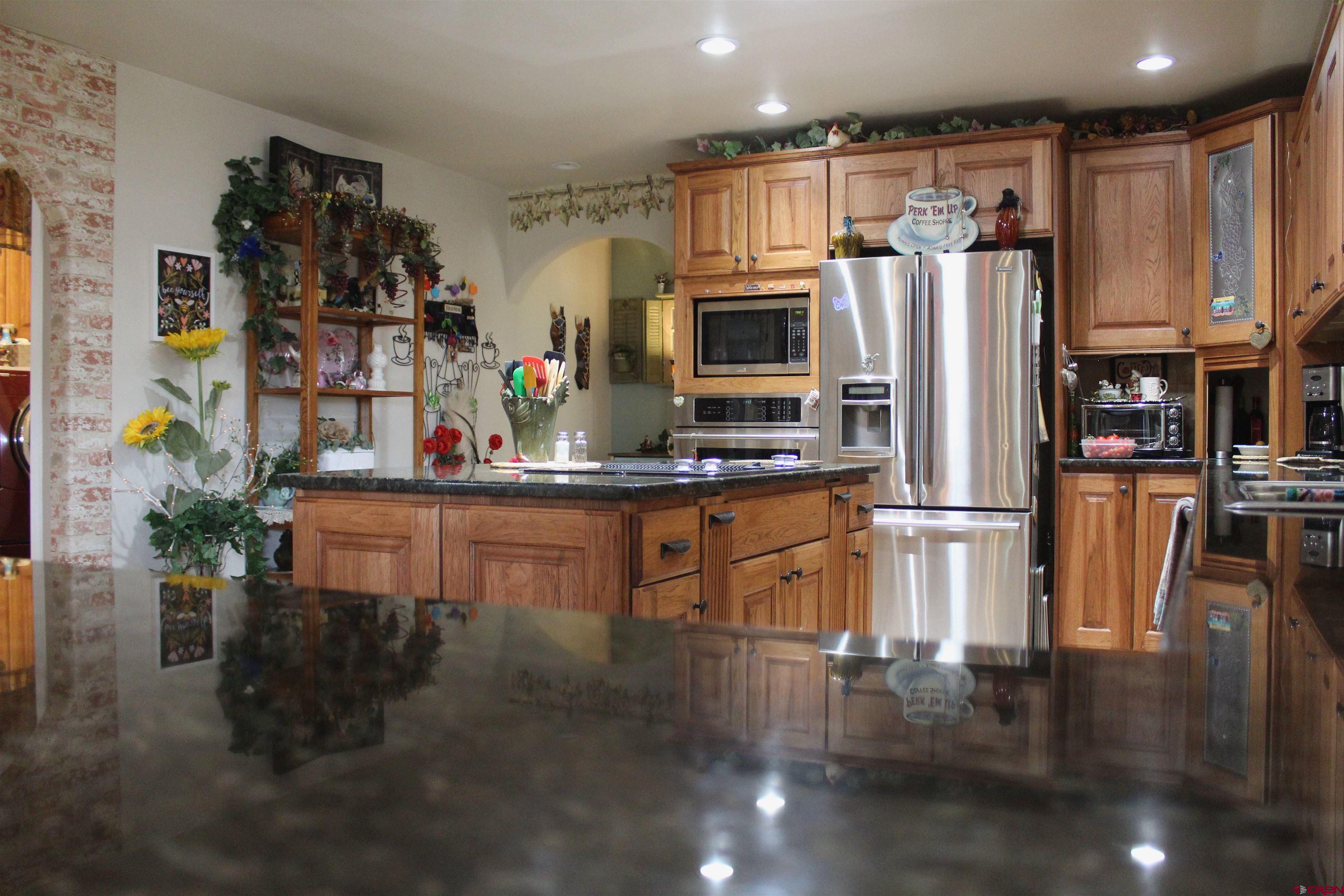 635 Northeast 2nd Street Cedaredge, CO 81413 - Photo 10 of 33 a kitchen with stainless steel appliances a refrigerator a stove a sink cabinets and a dining table with wooden floor
