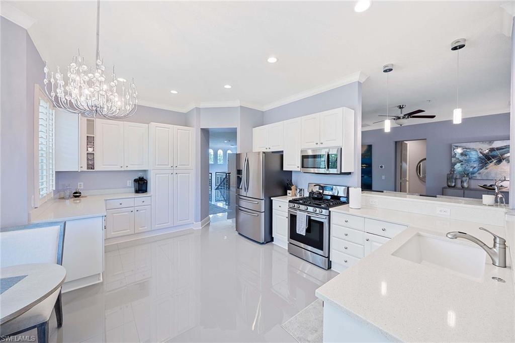 9202 Museo Circle, Unit 204 Naples, FL 34114 - Photo 13 of 37 a large kitchen with stainless steel appliances a refrigerator a stove a sink dishwasher and white cabinets with wooden floor
