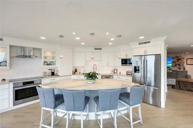a kitchen with stainless steel appliances granite countertop a stove a sink a refrigerator and a dining table