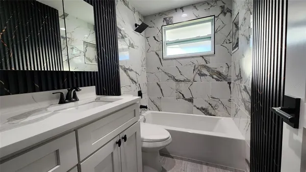 a bathroom with a double vanity sink toilet mirror and bathtub