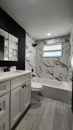a view of an empty room with wooden floor and a ceiling fan