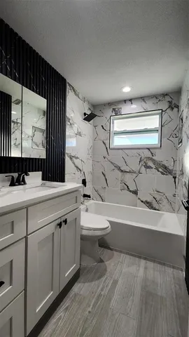 a view of an empty room with wooden floor and a ceiling fan