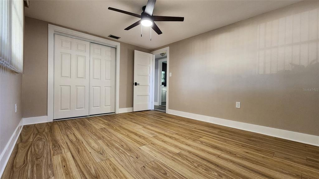 3629 Bedford Street New Port Richey, FL 34652 - Photo 15 of 29 a view of an empty room with wooden floor and a ceiling fan