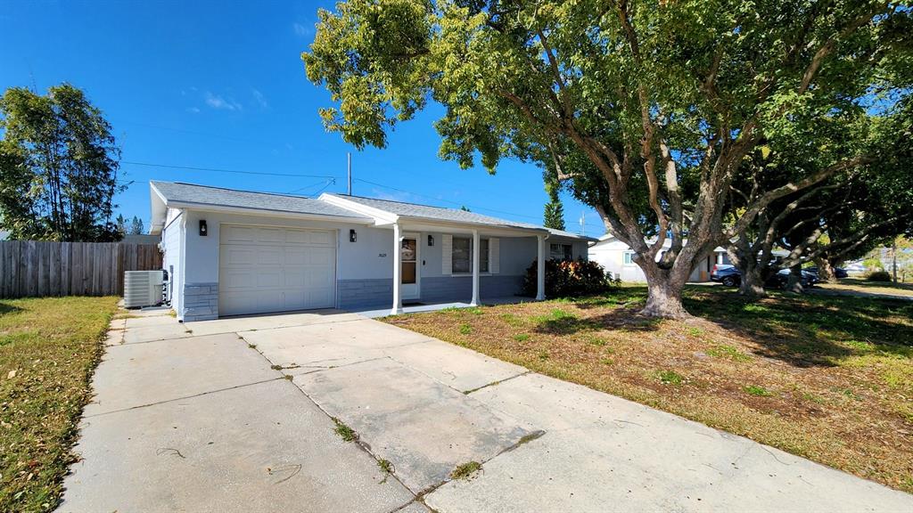 3629 Bedford Street New Port Richey, FL 34652 - Photo 25 of 29 a front view of a house with a yard and garage