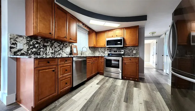 a kitchen with stainless steel appliances granite countertop wooden cabinets a stove top oven a sink and dishwasher
