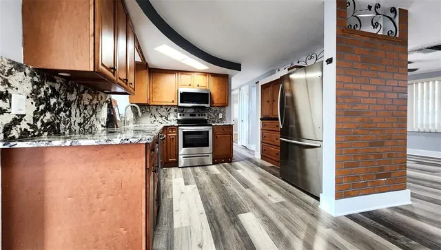 a kitchen with stainless steel appliances granite countertop a refrigerator a stove and a sink