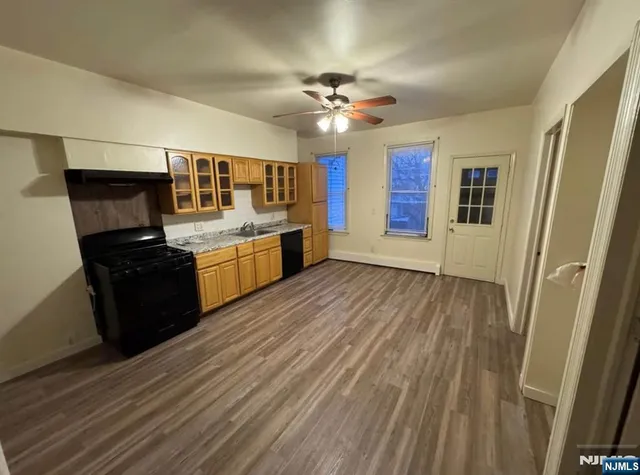 a kitchen with granite countertop a stove top oven a sink dishwasher and a refrigerator with wooden floor