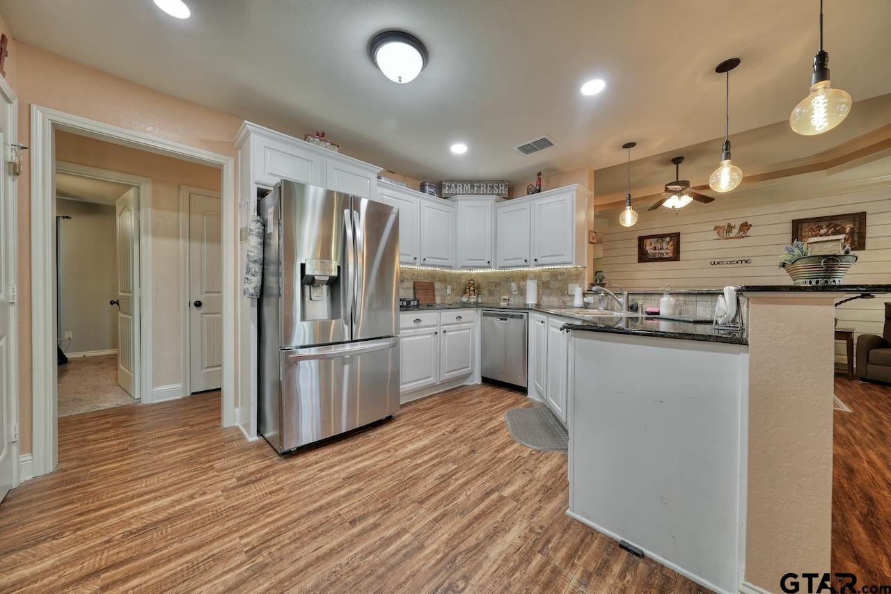 412 Elm Lane Lindale, TX 75771 - Photo 15 of 48 a kitchen with stainless steel appliances granite countertop a refrigerator a sink dishwasher a stove and white countertops with wooden floor
