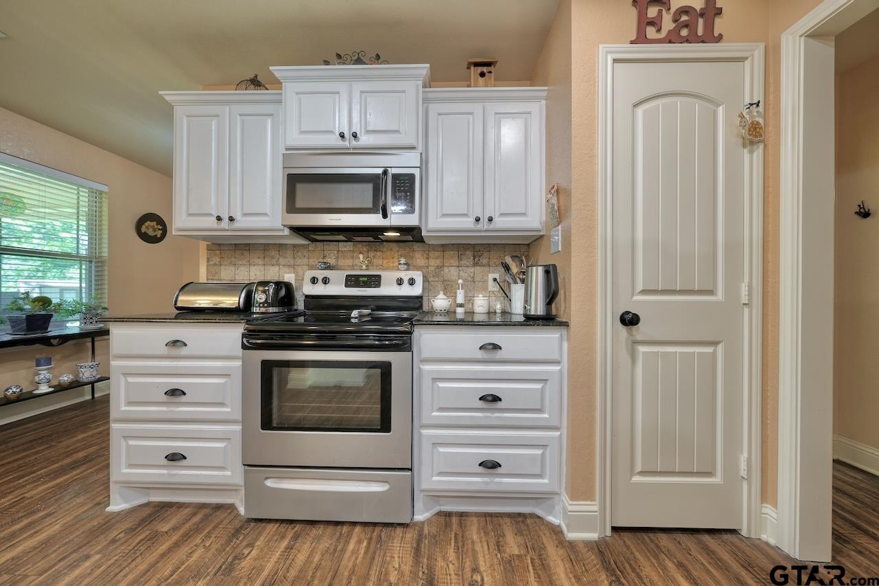 412 Elm Lane Lindale, TX 75771 - Photo 17 of 48 a kitchen with stainless steel appliances white cabinets and a stove top oven