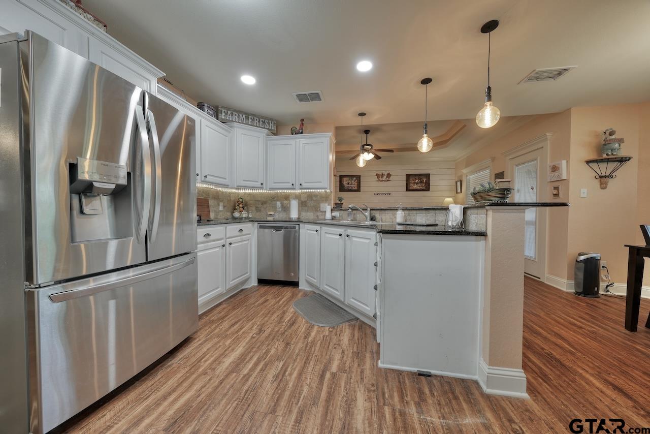 412 Elm Lane Lindale, TX 75771 - Photo 18 of 48 a kitchen with stainless steel appliances granite countertop a refrigerator a sink dishwasher a stove and white countertops with wooden floor