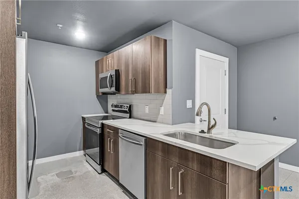 a kitchen with stainless steel appliances a sink and a refrigerator