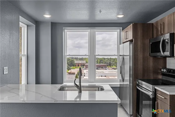 a kitchen with kitchen island a large window a sink and stainless steel appliances