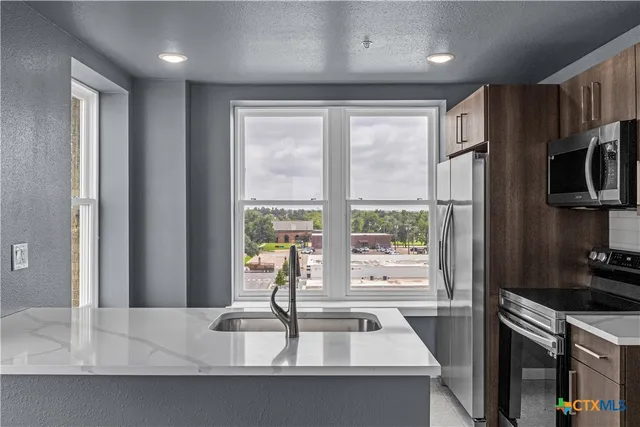 a kitchen with kitchen island a large window a sink and stainless steel appliances