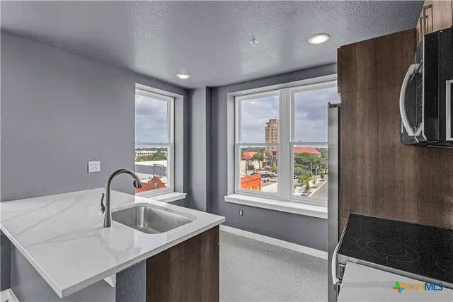 a kitchen with kitchen island a sink appliances and a window