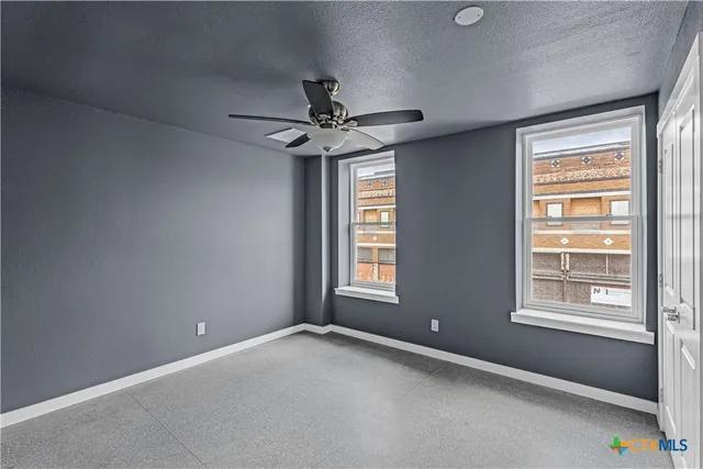 an empty room with windows and fan