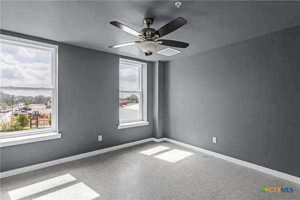 an empty room with windows and fan