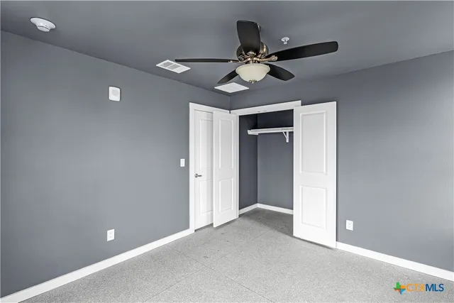a view of an empty room and chandelier fan