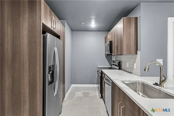 a kitchen with stainless steel appliances granite countertop a sink stove and refrigerator